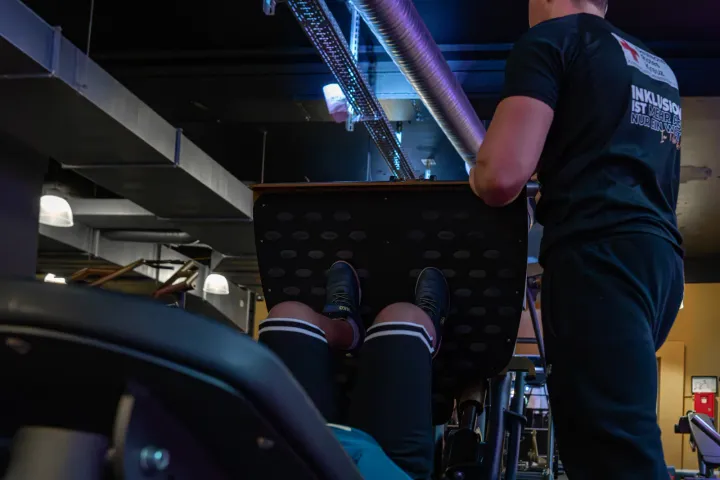 Limitless Trainer sichert einen Azubi beim Bankdrücken