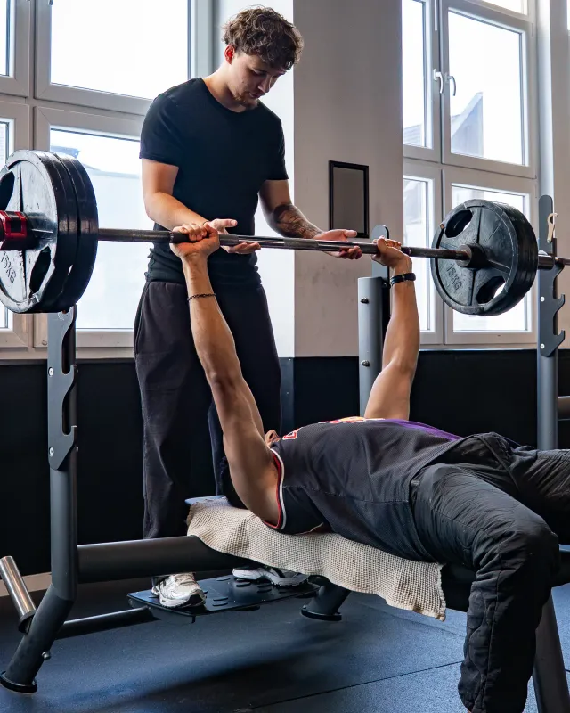 Trainer unterstützt Mitglied beim Bankdrücken im Limitless Studio